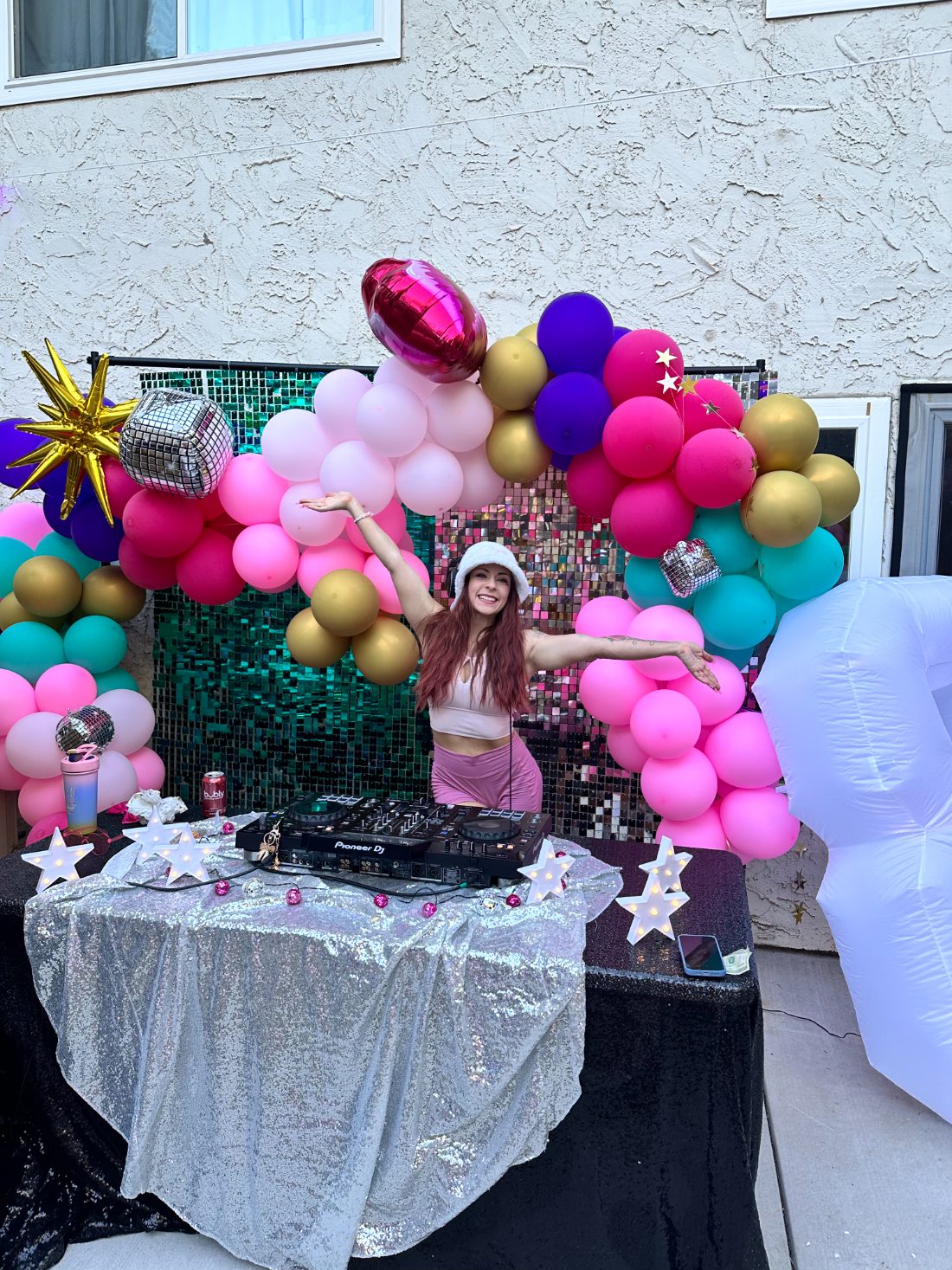 DJ Bunz behind the decks at a balloon-and-disco party setup